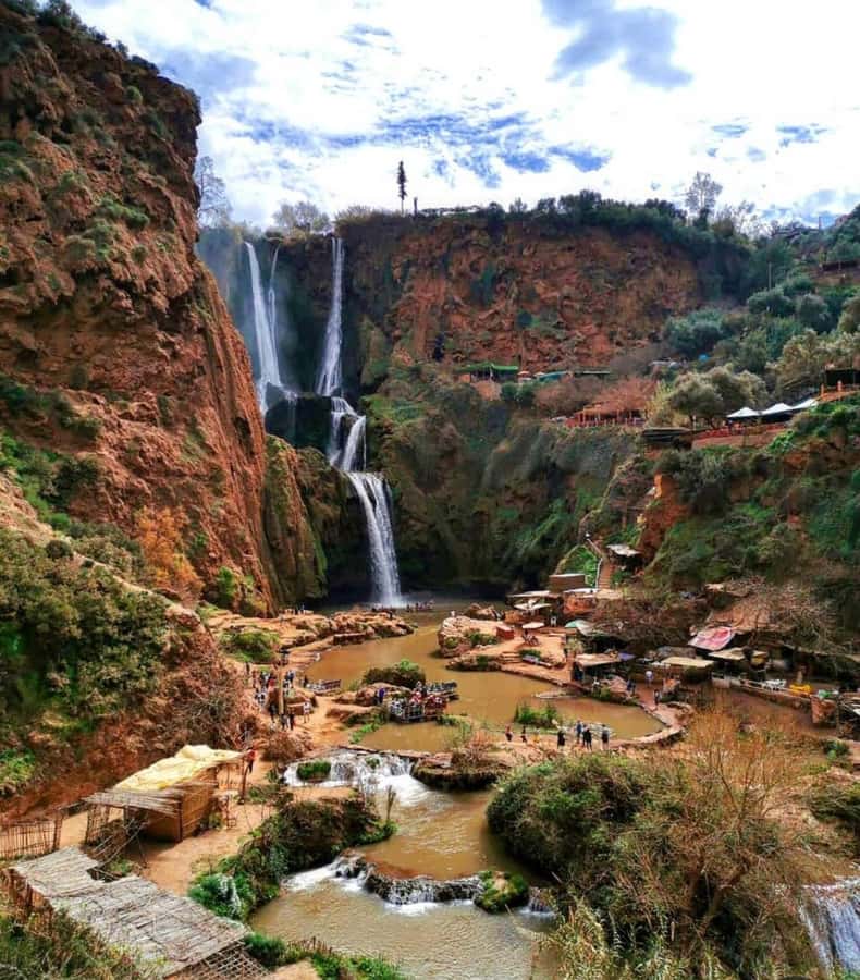 From Marrakech:Ouzoud Waterfalls Day Trip with Boat Tour - First views: red cliffs, trees, and three cascades
